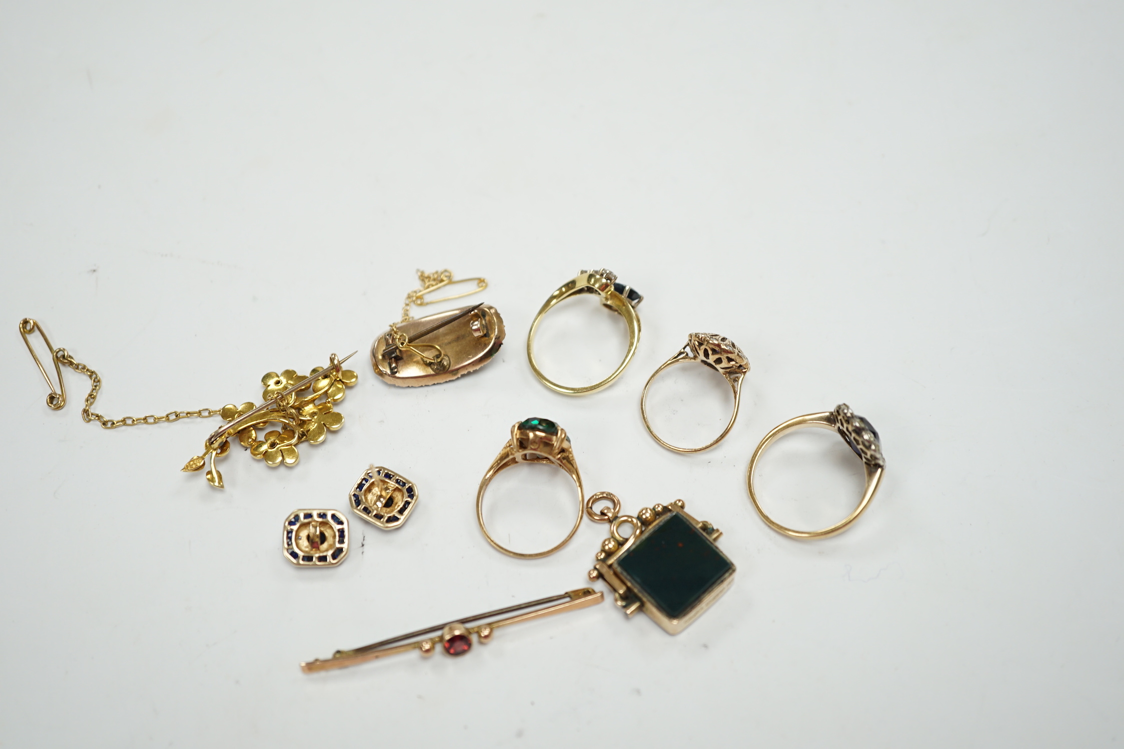 A 750 yellow metal, single stone sapphire and three stone diamond set crossover ring, size, three other yellow metal and gem set rings including a continental 875 white metal and 585 yellow metal, synthetic sapphire or s